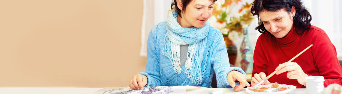 Photo of a woman helping another woman paint