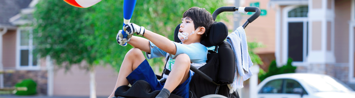 Photo of a young boy in a wheelchair hitting a ball with a bat